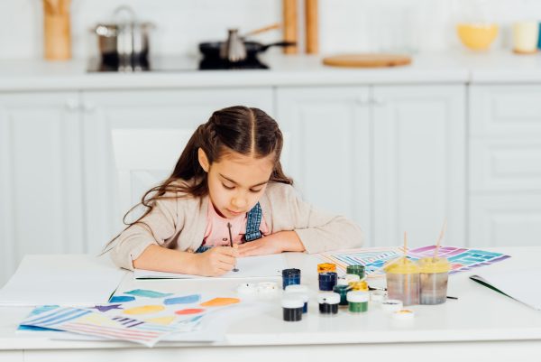 concentrated and cute kid painting on paper at home